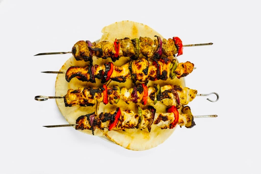 Flame-grilled chicken skewers on fresh pita bread